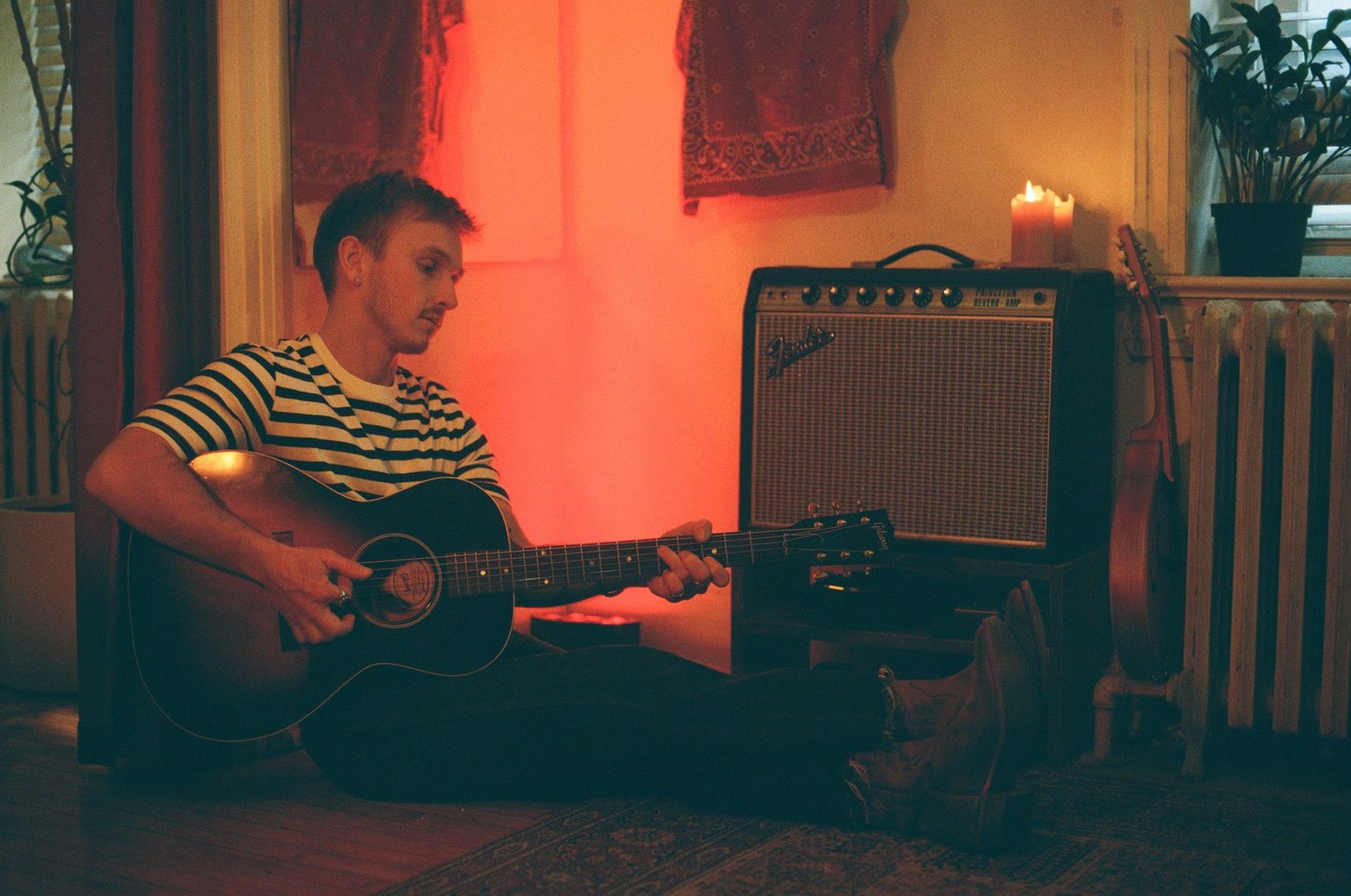Benji Crane playing guitar at home by candlelight